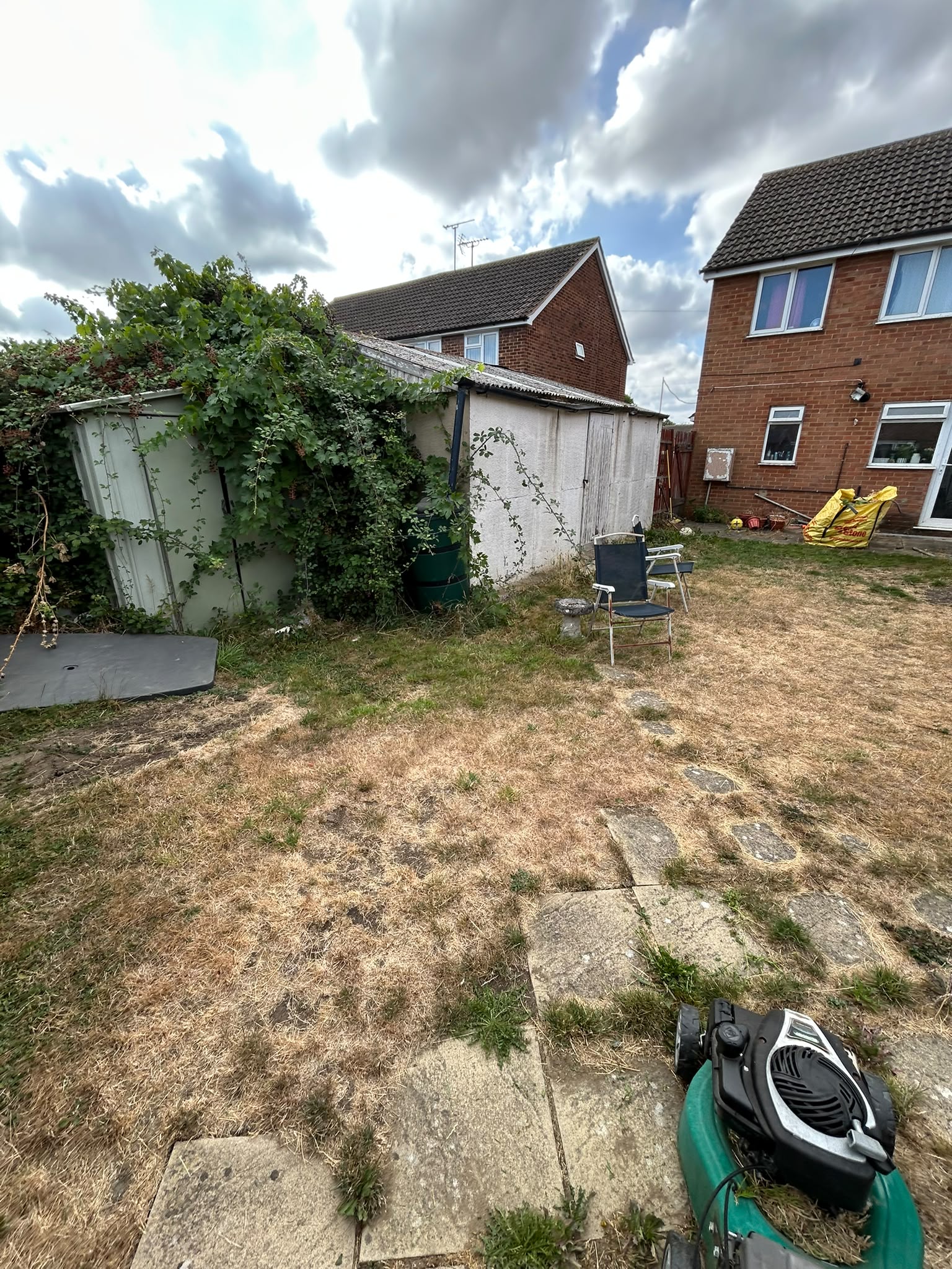 A tired, overgrown back garden being cleared with a mower and mini digger