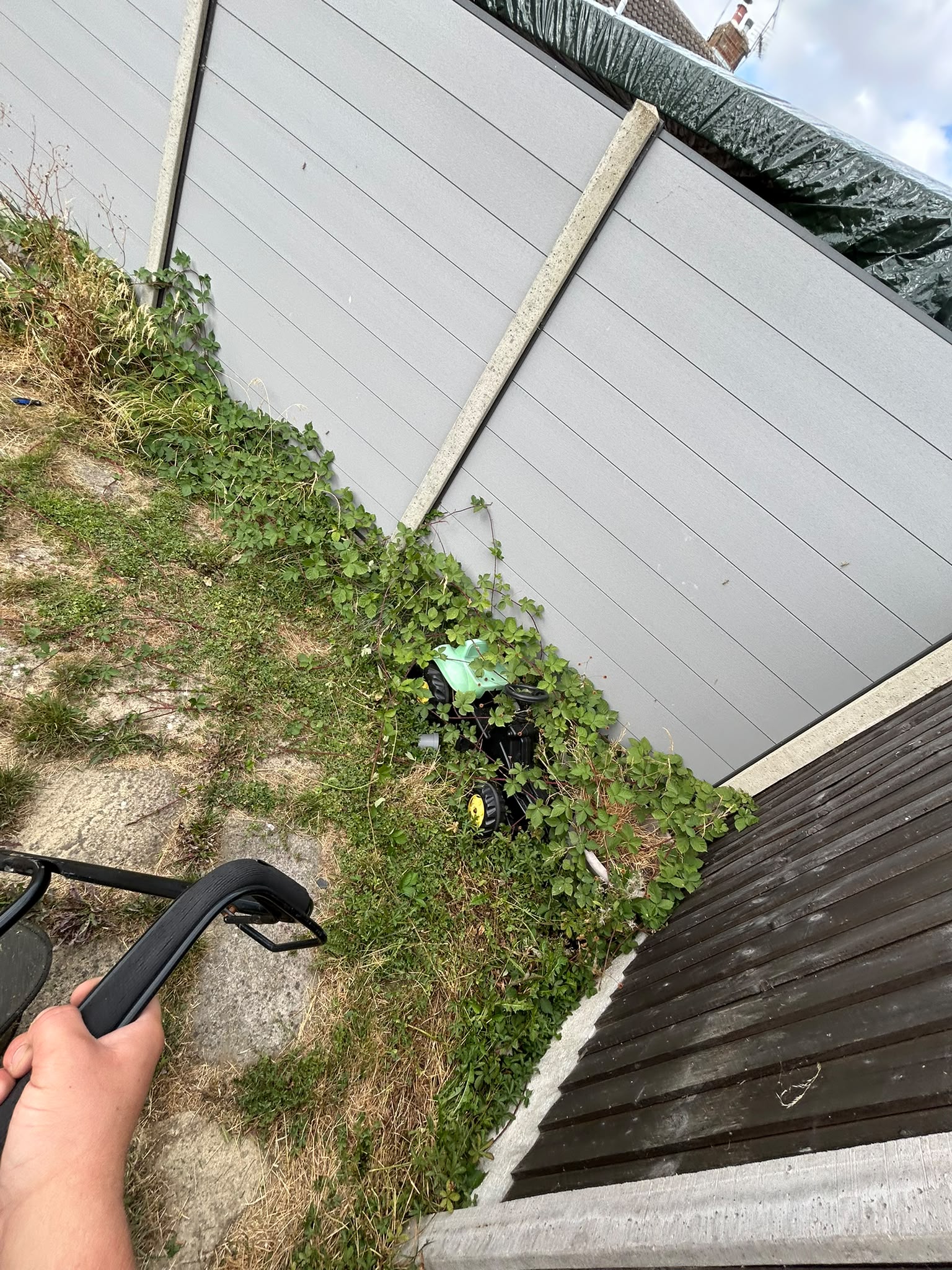 A neglected rear garden of long grass and brambles being cleared